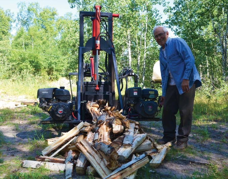 Local builder and inventor Leo Cote shuts down the engine of his award-winning invention, the Firewood Shear and Splitter, after shearing and then splitting an entire poplar
