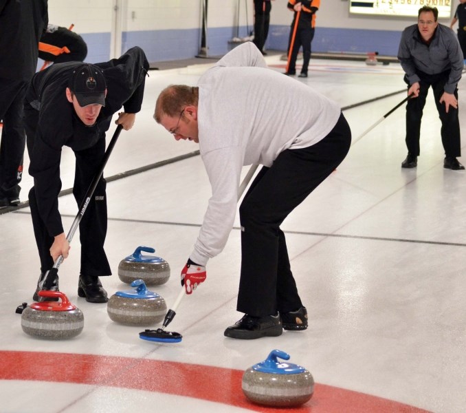 Lead Joe Rushton (left) and second Craig Pilipchuck (right) sweep a shot into the house while skip Ernie Maurier looks on. Their rink, representing Thermo Design Engineering, 