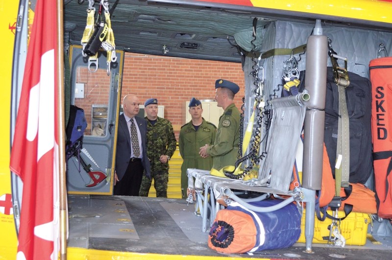 Minister Horne talks to several 4 Wing executives, including Base Commander Eric Kenny, in front of the helicopter used in the successful emergency transportation on Jan 15.