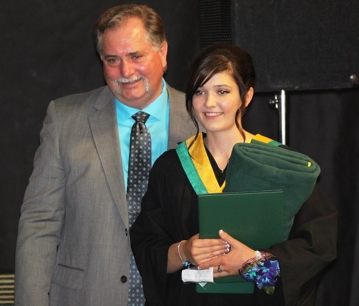 Graduate Morgan Pshyk stands with Principal Ken Pshyk after receiving her diploma.