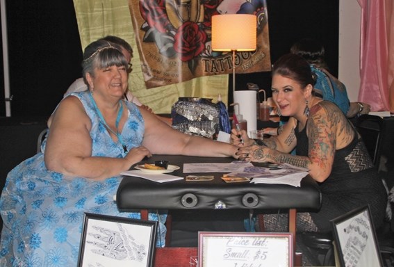 Lakeland Humane Society resource development coordinator Cathy Olliffe-Webster (left) gets a temporary henna tattoo from Sarah Pequegnat at the fifth annual Dawgs and Divas