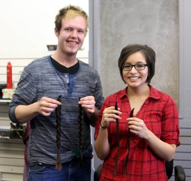 Jordan John (right) holds up the long braid stylist Steven Schweigert (left) helped cut off for Pantene&#8217;s Beautiful Lengths program.