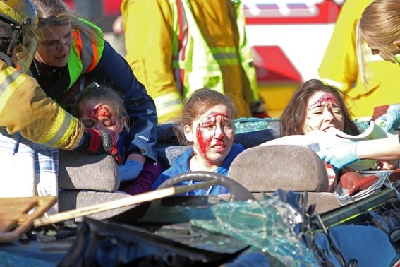 Students, covered in fake blood, are helped out of the car and into neck braces by emergency responders after the roof of the car is removed by the jaws-of-life.