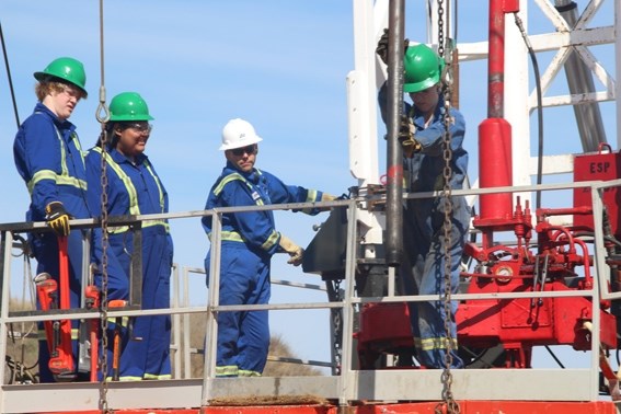 Grade 11 BCHS students Brendan Collins and Konnr Quinney (left) watch with instructor Kevin Rash as Megan Paddison, Grade 12, participate in an oil rig demonstration at the