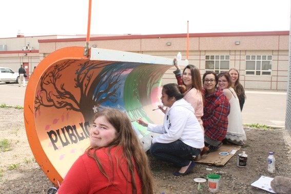 The Assumption Junior/Senior high school Art 30 class paints the blade of a city snowplow. From left to rightL Natalie War, Divine Tanjay, Paige Collins, Anna-Claire