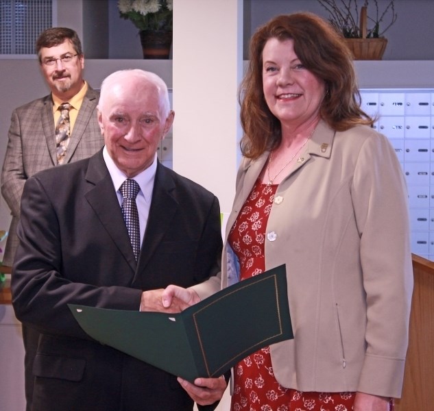 Minister of Seniors and Housing Lori Sigurdson presents a recognition certificate to Lakeland Lodge Chair Ray Prevost while Bonnyville Mayor Gene Sobolewski looks on.