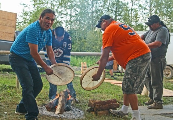 The Northlands Dene drummers heat their drums between songs. The practice has both a spiritual side &#8211; the fire connects them with nature and the creator, and practical