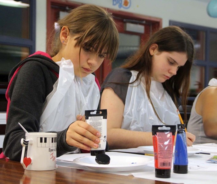 Sara Gamblin, 13, gets her colours ready for painting night at the BEE Café, while Bryce Lokszyn, 16, sketches out a design.