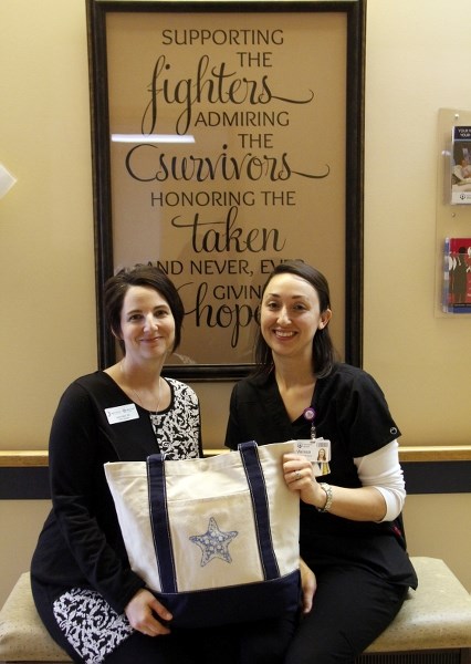 Robbi Allen, cancer patient navigator, and oncology nurse Melissa Fredette, both of the Bonnyville Cancer Clinic, show off one of the chemo comfort bags being handed out to