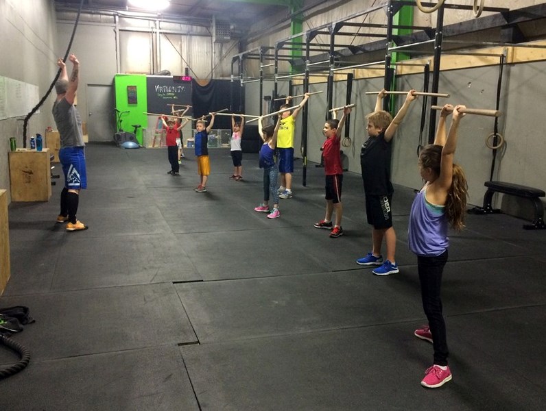 Ryan Bardick leads a group of young CrossFit athletes through a warm up.
