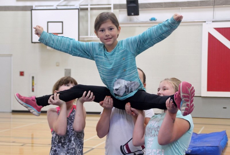 Nataliah Bigstone, Aiyanna Gadwa, and Dominik Dubeau hold up Jaylin Tootoosis during Premier Academy practice Wednesday, Oct. 4, at Duclos School.