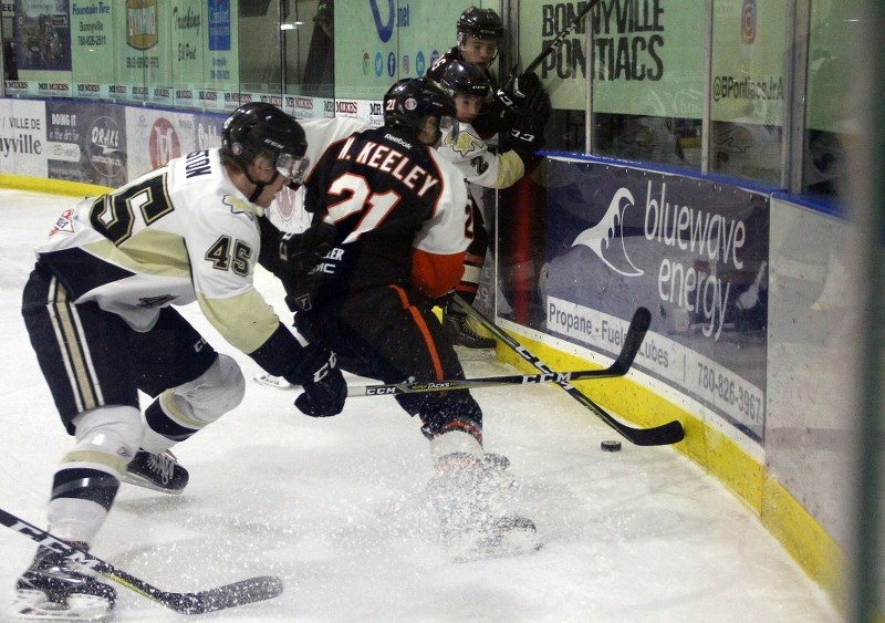 Zach Aston chases Dragons forward Nate Keeby into the corner during their game in Bonnyville on Saturday, Dec. 9.