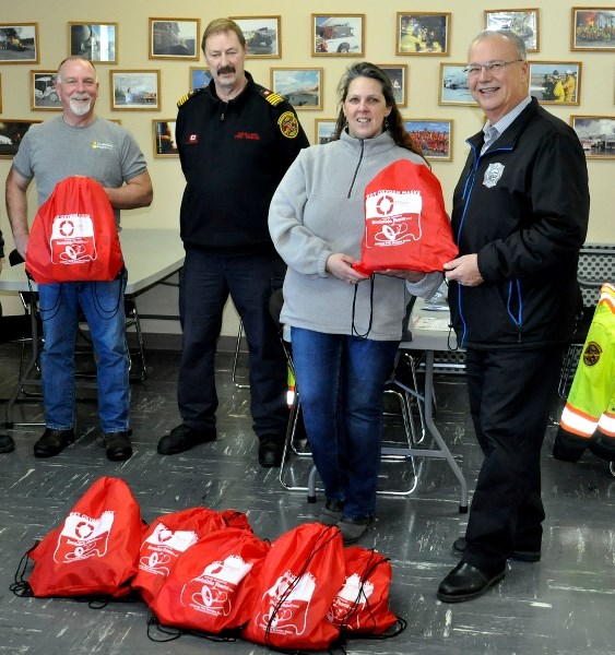 (right to left) BRFA chief Brian McEvoy, MD resident Silke Skinner, and Cold Lake Fire-Rescue deputy fire chief Norm Hollis accept 11 pet oxygen masks from Invisible Fence