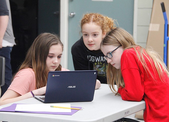  Vanessa (far left) helps fellow students Ariana, Grade 6, and Isabelle, Grade 6, with their program.
