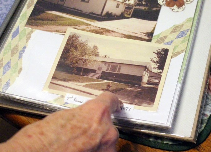  Aline points to a photograph of one of their homes together.