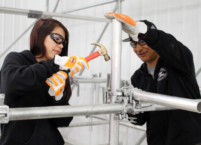  Alesa LaRocque (left) tries her hand at the triple clamp with the assistance of Dean Cardinal from Seven Lakes Oilfield Services.