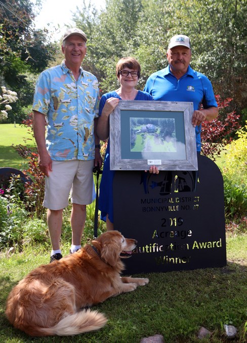  Bruce and Cynthia Sloychuk claimed the 2019 Rural Beautification Acreage Award. Coun. Mike Krywiak (far right) presents the couple, and Rudy their dog, with the honours.