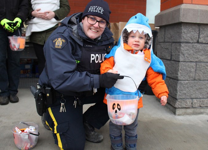  During the Bonnyville RCMP’s Halloween Safety Program, two-year-old Jacob Bird takes a pumpkin from Cst. Megan LeTang. - Photo by Robynne Henry