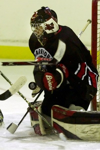 Matthew Johnson, goalie for the Saddle Lake Warriors, tries to glove a puck during a game at Saddle Lake Manitou Kihew arena on Friday.