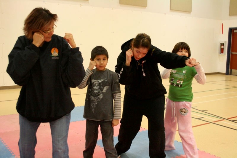 Nitasha Tiger Half, an amateur kickboxer, walks students through some moves during a six day course in Saddle Lake over the Christmas break. Following her lead are Val