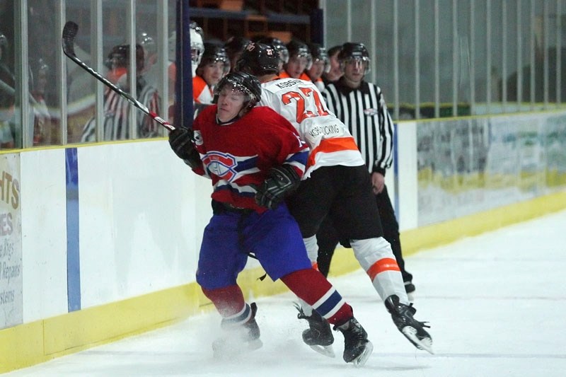 Brett Romanovich (13) of the St. Paul Canadiens takes a check from the back from Matt Kobsar (27) of the Wainwright Bisons during the third period of Sunday afternoon&#8217;s 