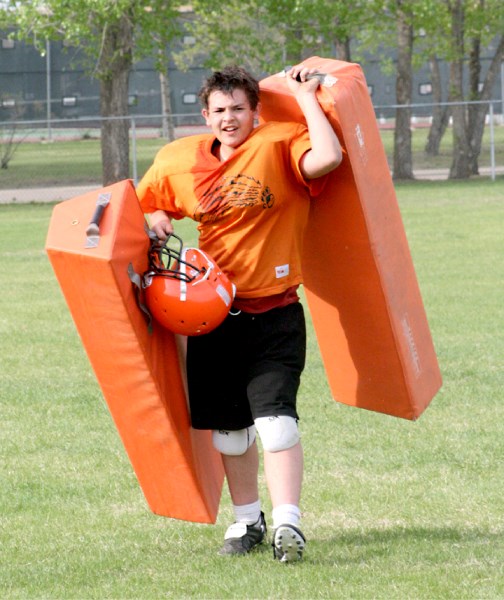 Eric Robinson, a new member of the St. Paul Bengals football club, brings in equipment after a hard practice on Thursday.