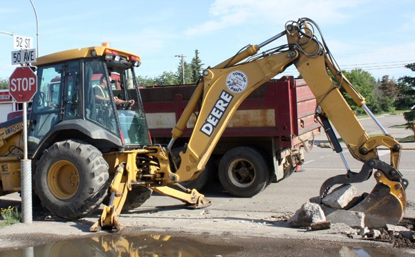 Albert Munro with the Town of St. Paul digs up a section of old sidewalk. The Town replaced several blocks of downtown sidewalks this summer.