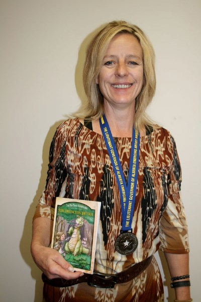 Local writer Diane Robinson proudly sports the medal she received for winning a Lieutenant Governor of Alberta Emerging Artist award. She also holds the book, Sir Princess