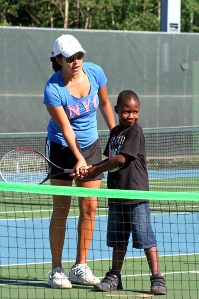 St. Paul Tennis Club instructor Carolina Escamilla helps Francis Adebayo work on his swing during practice last week.