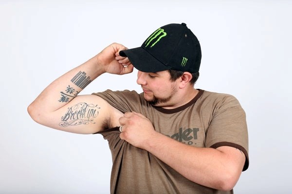 Tyson Newby shows off his arm, which has a few tattoos that are personally important to him, including his wedding anniversary, his daughter&#8217;s name, and Chinese
