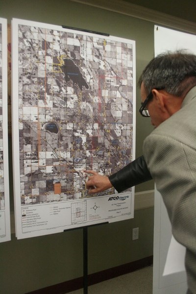 Pierre Lamoureux examines a map&#8217;s routes for a proposed transmission line at an Oct. 11 meeting in St. Paul. The map shows two potential routes, a preferred east route