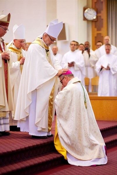 Bishop Paul Terrio (kneeling) receives a blessing from Bishop Luc Bouchard, the previous bishop of the Diocese of St. Paul, at Terrio&#8217;s ordination on Dec. 12. Pictured