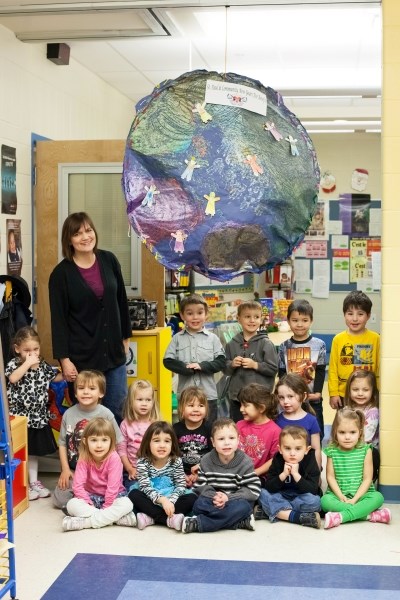 Playschool teacher Aline Beaudoin stands alongside her students at Ecole du Sommet, showing off the globe they created as a decoration for the upcoming New Year&#8217;s Eve