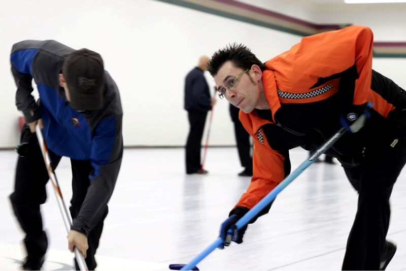 Collin Kupchenko (right) furiously sweeps the ice in the Mallaig Men&#8217;s Bonspiel C event quarter-finals on Sunday morning