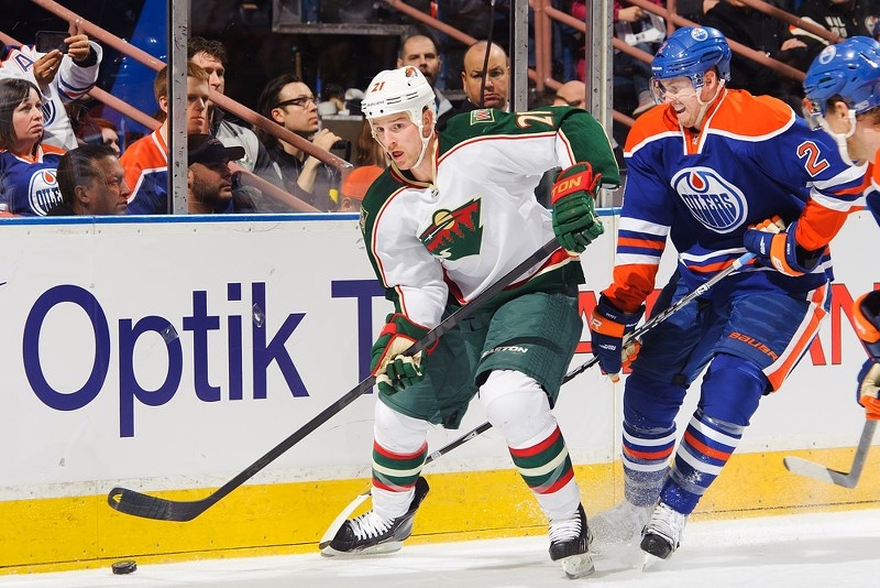 Kyle Brodziak of the Minnesota Wild looks for an open man while being pressured by Edmonton Oiler Jeff Petry during the Wild&#8217;s 3-1 victory at Rexall Place last Thursday.