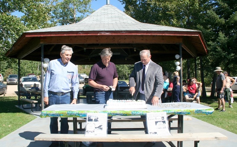 Russ Kowtun, one of the founders of Stoney Lake Park, St. Paul County Reeve Steeve Upham, and Division 2 Coun. Dwight Dach cut and prepare a cake to celebrate Stoney