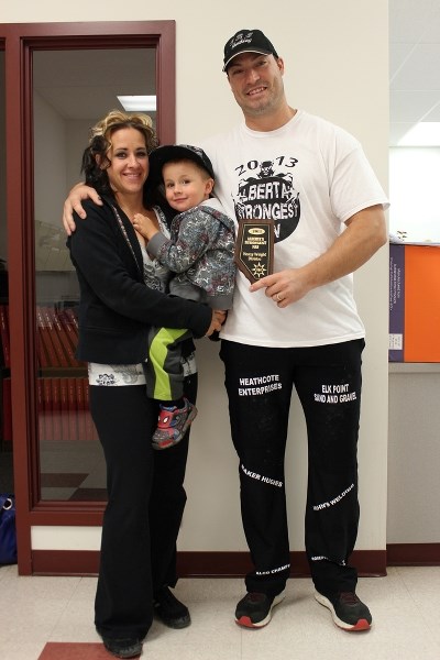 Elijah Hall (right) stands with his wife Maxine, his son, Lincoln, and his plaque for Alberta&#8217;s Strongest Man, which he won in Calgary on Oct. 5.