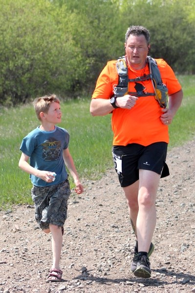 Elk Point solo runner Dave McNamara closes out the final leg of the Iron Horse Mini on Saturday afternoon while his son Heath jogs alongside for morale.