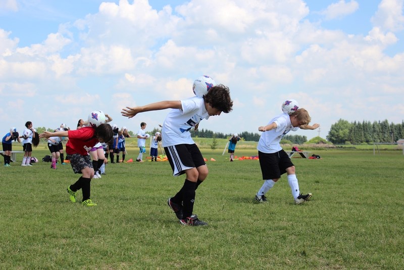(From left) Jon Warkentin, Nathan Barlad and Logan Hellquist balance soccer balls between their shoulder blades during a race at the British Soccer Camp last week.
