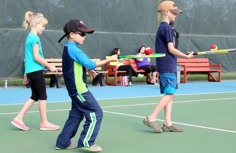 Katherine Thiessen, Kurt Poulin and Ty Thiessen move around while balancing tennis balls on their racquets at the St. Paul Tennis Club camp last Monday morning