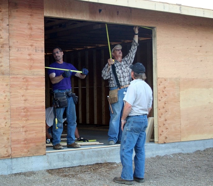 Claude Corbiere (left), and Louch Gratton carry out the construction of a bazar building as Mark Galas looks on , at the Haying in the 30s site, south of Mallaig, on July 24.