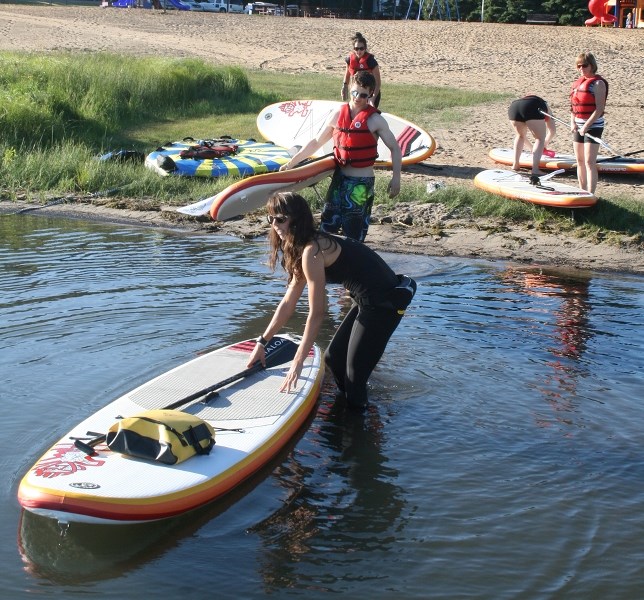 Standup paddle-board instructor Alyssa Kozicky enters the waters at Lac Bellevue during a paddle-board class.