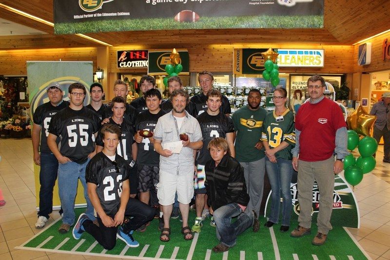Members of the St. Paul Lions pose with Eskimos running back John White. The Lions accepted a donation of Eskimos tickets from the St. Paul Co-op and Molson.