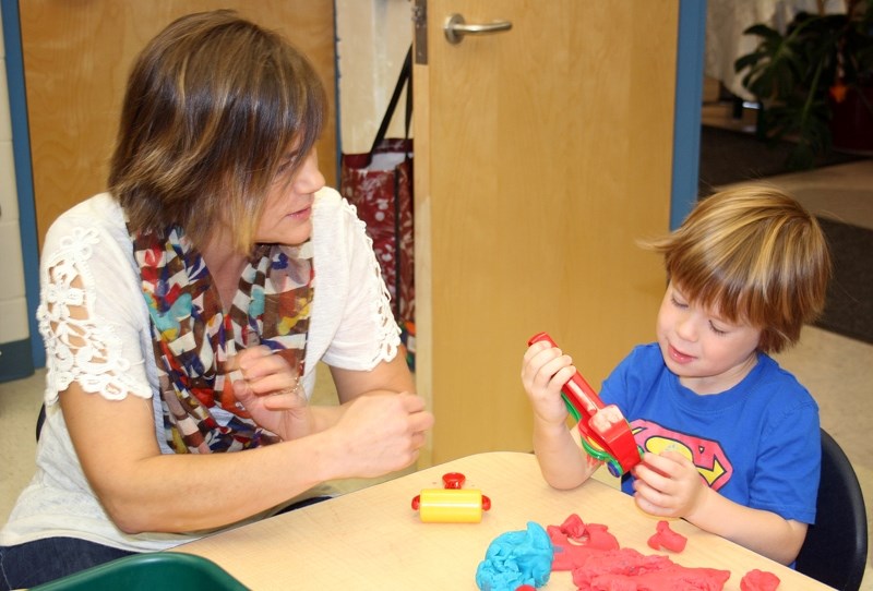 Playschool teacher Aline Beaudoin sits with Noah Haugen as the pair work on play-doh during class last week. In return for her years of commitment to students and their