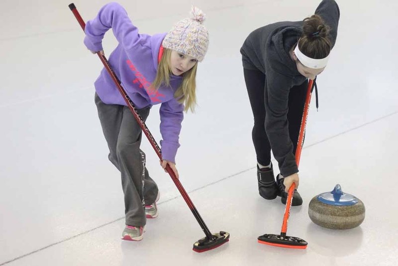 Rebecca Kotowich and Trista St. Arnault use their brooms to help guide the rock down the ice.
