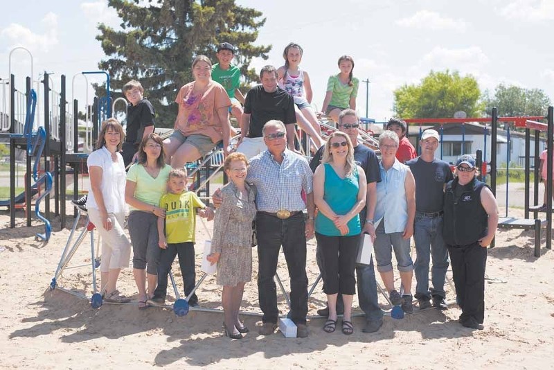 Volunteers who supported the Vilna School playground project gather around some of the equipment for a group photo during the official park opening, June 24.