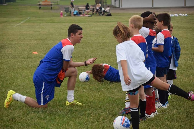 Coach Tim Degrot gives instructions to the five to nine-year-olds in his group at the British Soccer Camp prior to playing in a scrimmage on Tuesday.