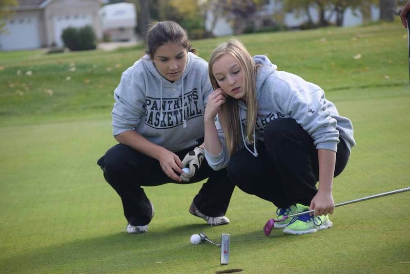 Kelsey Kurek (left) and Devyn Dubelt of Glen Avon School study the first hole green prior to Kurek&#8217;s attempt to sink the ball in the hole