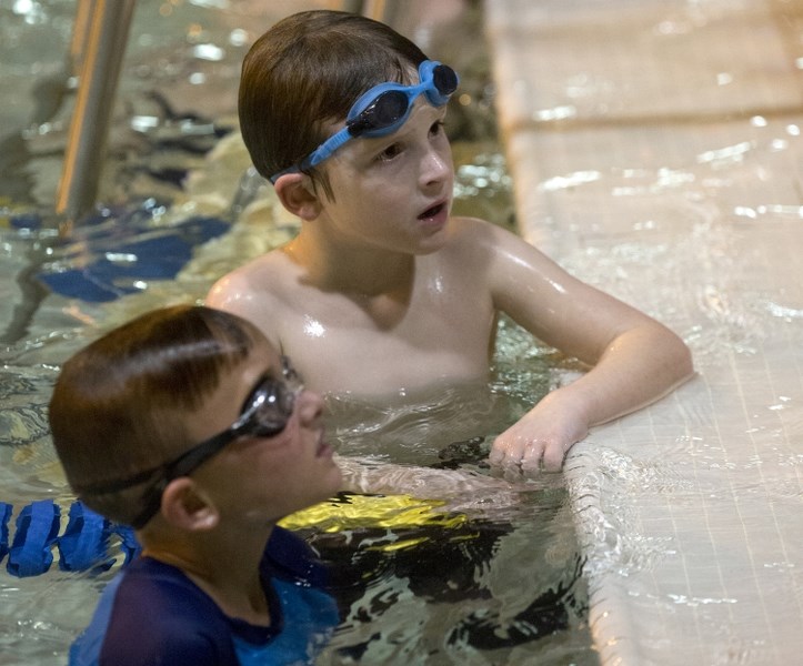 Cameron Robinson takes a short break with fellow swimmer Mathis Poulin from swimming laps at the Barracudas&#8217; swimathon last Thursday evening.