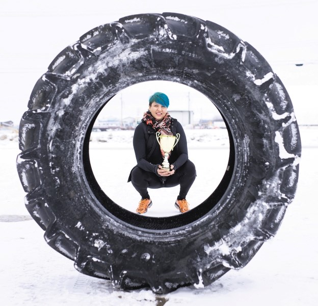 Angie Cardinal displays a tractor tire she picked up (literally) at Fountain Tire last week, a tire that she practices flipping for fun. Her hard-core workouts saw her win a
